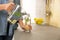 Young woman pouring lemon water into glass in kitchen. Space for text