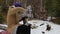 Young woman pours tea from a thermos near a stream in the winter forest