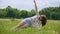 Young woman practices yoga in green grass, outdoor yoga closer to nature asana