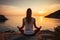 Young woman practices yoga on the rocky coast by the sea at sunset