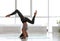 Young woman practicing headstand with splits in studio