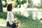 Young Woman Practicing Meditation near Water in the Nature