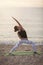 Young woman practicing yoga on the beach. Reverse Warrior Pose, Viparita Virabhadrasana. Outdoors sports. Healthy living.