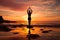 A young woman practicing yoga on the beach at sunset