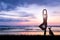 Young woman practicing yoga at beach on sunset