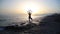 Young woman practicing yoga on the beach at sunset.