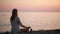 Young woman practicing yoga on the beach at sunset. calm sea