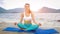 Young woman practicing yoga on the beach at sunset. Lotus pose