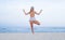 Young woman practicing yoga on the beach. Vrksasana pose