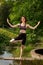 Young woman practicing yoga on a bridge near a decorative lake in the park. Summer day, yoga concept