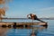 Young woman practicing yoga exercise at quiet wooden pier with city background. Sport and recreation in city rush