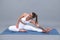 Young woman practicing yoga extended asana in studio. Sporty woman sitting on mat, doing yoga pose.