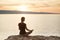 Young woman practicing yoga near the sea at sunset. Harmony, meditation and travel concept. Healthy lifestyle