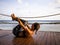 Young woman practicing yoga outdoor. Back stretch exercise on wooden floor. Healthy life. Bali, Indonesia