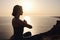 Young woman practicing yoga over sunset sea