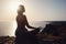 Young woman practicing yoga over sunset sea