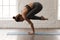 Young woman practicing yoga, standing in Crane pose, Bakasana exercise