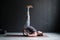 Young woman practicing yoga, standing in Viparita Karani exercise, using wheel