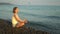 Young woman practises yoga and meditation at the beach. Sunset