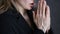 Young woman is praying. close-up female hands holding chain with a cross