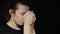 Young woman praying on a rosary with a cross in the dark