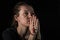 Young woman praying to god with prayer beads with a crucifix on the cross