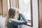 Young woman praying by window