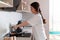 A young woman is preparing breakfast in the kitchen, frying eggs. Side view. The concept of a home-cooked meal