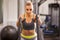 Young woman preparing to work out with battle ropes at a gym