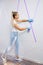 Young woman preparing wall for painting standing on ladder applying masking tape on wall. Diy project