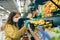 Young woman in a protective mask choosing lemons in a store