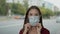 Young woman in a protective mask on her face. Traffic on background.