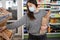 Young woman in a protective mask in the store buys fresh hot bread in the department. Shopping for food.