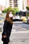 Young woman with protective mask on the street in the city with air pollution, asking for a taxi, city background