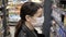 Young woman in protective mask in supermarket purchased products. Protection from coronavirus, purchase of food for quarantine.