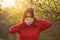 A young woman in a protective medical mask covers her ears from false news with her hands. Massive