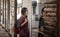 A young woman with a protective medical mask on her face stands in front of a closed store and looks in the window