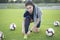 A young woman pulls on her football socks and ties her shoelaces. Young girl with dreadlocks on the green grass of a football