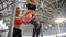 Young woman pulls up on the crossbar in the sports hall. Pumping lower parts of her body with trainer helping her