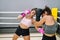 A young woman punching her partner in the stomach during boxing practice in the ring at a gym