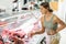 Young woman purchaser buying meat in butcher shop