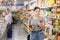 Young woman purchaser choosing tomato juice in supermarket