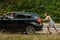 Young woman pushing broken car with man on road