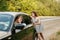 Young woman pushing broken car with man on road