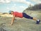 Young woman pushups outdoors in nature.