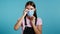 Young woman puts on face medical mask during coronavirus pandemic. Portrait on blue background. Protection with