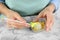 Young woman putting cake pop into yellow sprinkles at white marble table