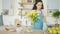 Young woman is putting flowers in a vase on the dining table