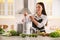 Young woman putting fresh kiwi and apple into juicer at table in kitchen