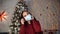 Young woman putting medical mask on face on background of Christmas tree. Charming brunette in protective mask